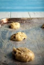 Three cookie shaped raw doughs with chocolate chips placed on the baking tray spread with butter