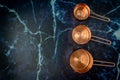 Three of copper measuring cups on dark blue marble background Royalty Free Stock Photo