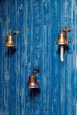 Three copper old vintage bells, doorbell, rope on a wooden blue aged wall. Concept decor element in interior of deck, cabin of Royalty Free Stock Photo