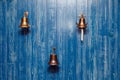 Three copper old vintage bells, doorbell, rope on a wooden blue aged wall. Concept decor element in interior of deck, cabin of Royalty Free Stock Photo