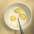 Three cracked eggs in a bowl with milk and a utensil sticking out of the bowl