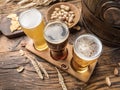 Three craft beers on wooden beer flight board. Top view of beer glasses, snacks and beer cask at the background Royalty Free Stock Photo