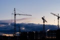 Three cranes and an unfinished residential skyscraper. Dramatic sky dusk landscape. Residential building construction Royalty Free Stock Photo