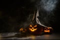 Three creepy Halloween grinning pumpkins glow in the dark among the fog. jack-o-lantern in a witch hat on a black