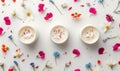 Three creme jar blank mockups nestled amidst delicate flower petals on a white background Royalty Free Stock Photo