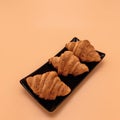 Three croissants lie in a row on a black rectangular plate. Royalty Free Stock Photo