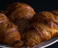 Three croissants on a white plate, dark background, front view Royalty Free Stock Photo