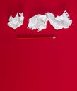 Three crumpled white pieces of paper and a red wooden pencil on a red background