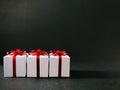 Three white gift boxes together with red ribbon on black background.