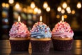 three cupcakes with lit candles on a wooden table