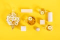 Three cups of camomile tea, transparent teapot and wood geometric shape on yellow background. Creative concept Natural