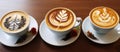 Three cups of cappuccino on saucers on a wooden table Royalty Free Stock Photo