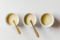 Three cups of cream and a wooden spoon. AI generative image