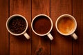 Three cups of espresso, freshly ground coffee and coffee beans on a wooden table