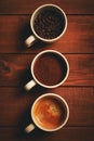 Three cups of espresso, freshly ground coffee and coffee beans on a wooden table Royalty Free Stock Photo