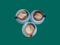 three cups of hot cappuccino coffee on a teal background Royalty Free Stock Photo