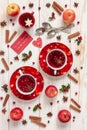 Three cups with hot Christmas fruit drink with spices and berries. Christmas background with holly, red apples, cinnamon, anise
