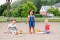 Three cute Caucasian and hispanic latin toddlers babies children sitting in sandbox playing with plastic colorful toys Royalty Free Stock Photo