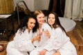 Three cute females in bath robes in the indoor pool. Women friends on vacation at the Spa Royalty Free Stock Photo