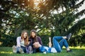 Three cute girlfriends resting the park. Young attractive girls on a green lawn talking and laughing. Concept of outdoor