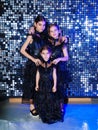 three cute girls in a black long curvy dress dancing at the disco. shiny wall