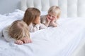 three cute kids girl and boys brothers and sister smiling lying on bed at light modern bedroom Royalty Free Stock Photo