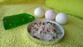 Three cute little bombs for the bath, a large green soap and bath salt with flower petals on yellow towel Royalty Free Stock Photo