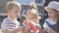 Three cute little Children enjoys delicious ice cream cone. Child eating watermelon popsicle. Kids Siblings snack sweets Royalty Free Stock Photo