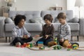 Three cute multiethnic boys play wooden railway at home