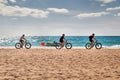 Three cyclists ride along a sandy beach