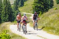 Three cyclists riding mountain bike in sunny day on a mountain road, Romania