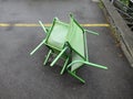 Three dancing green chairs on asphalt