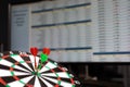 Three Darts hit the target against the background of exchange statistics on the monitor screen