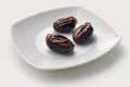 Close up view of dates fruit also known as kurma on a white plate, with white background,. Created with generative AI technology.