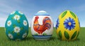 Three Decorated Easter Eggs with Rooster and Floral Designs on Green Grass Under Blue Sky Royalty Free Stock Photo