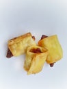 Three deep-fried, golden spring rolls or savory snacks on a clean white background. Royalty Free Stock Photo