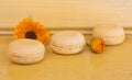 Three delicate yellow macaroons almond cakes on a yellow background with calendula flowers