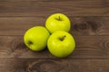 Three delicious golden grenni apples on dark wooden table. Ripe whole apples group heap, tasty healthy fruits Royalty Free Stock Photo