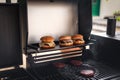 Three delicious homemade burgers of beef, cheese and vegetables stand in a bbq grill. Homemade beef burgers Royalty Free Stock Photo