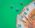 Three dice showing a five and 4 50 euros bills on the corner, on a green background Royalty Free Stock Photo