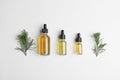 Three different bottles with essential oils between pine branches on white background