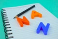 Three different colored letter blocks and a pencil placed on a white note paper diary Royalty Free Stock Photo