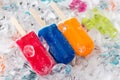 Three different coloured popsicles lying on ice on tray Royalty Free Stock Photo