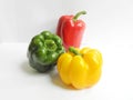 Three different and contrasting colors of fresh bell peppers, green, red, glossy yellow, and on a white background Royalty Free Stock Photo