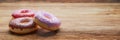 Three different and delicious donuts on a brown and rustic table. 3D illustration. Royalty Free Stock Photo