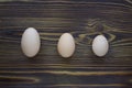 Three different eggs laying on the wooden background