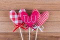 Three different fabric hearts on wooden sticks with ribbon bows placed on a wooden background. Photo Valentines Day