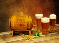 Three different glasses of light beer, a wooden barrel, ears of barley and hops on a wooden table Royalty Free Stock Photo