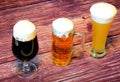 Three different glasses with different types of beer, light, dark and wheat on a wooden table Royalty Free Stock Photo