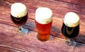 Three different glasses, with different types of dark beer, stand in a row on a wooden table Royalty Free Stock Photo